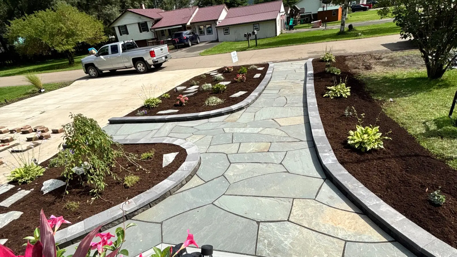 A flagstone walkway curving between freshly mulched planting beds