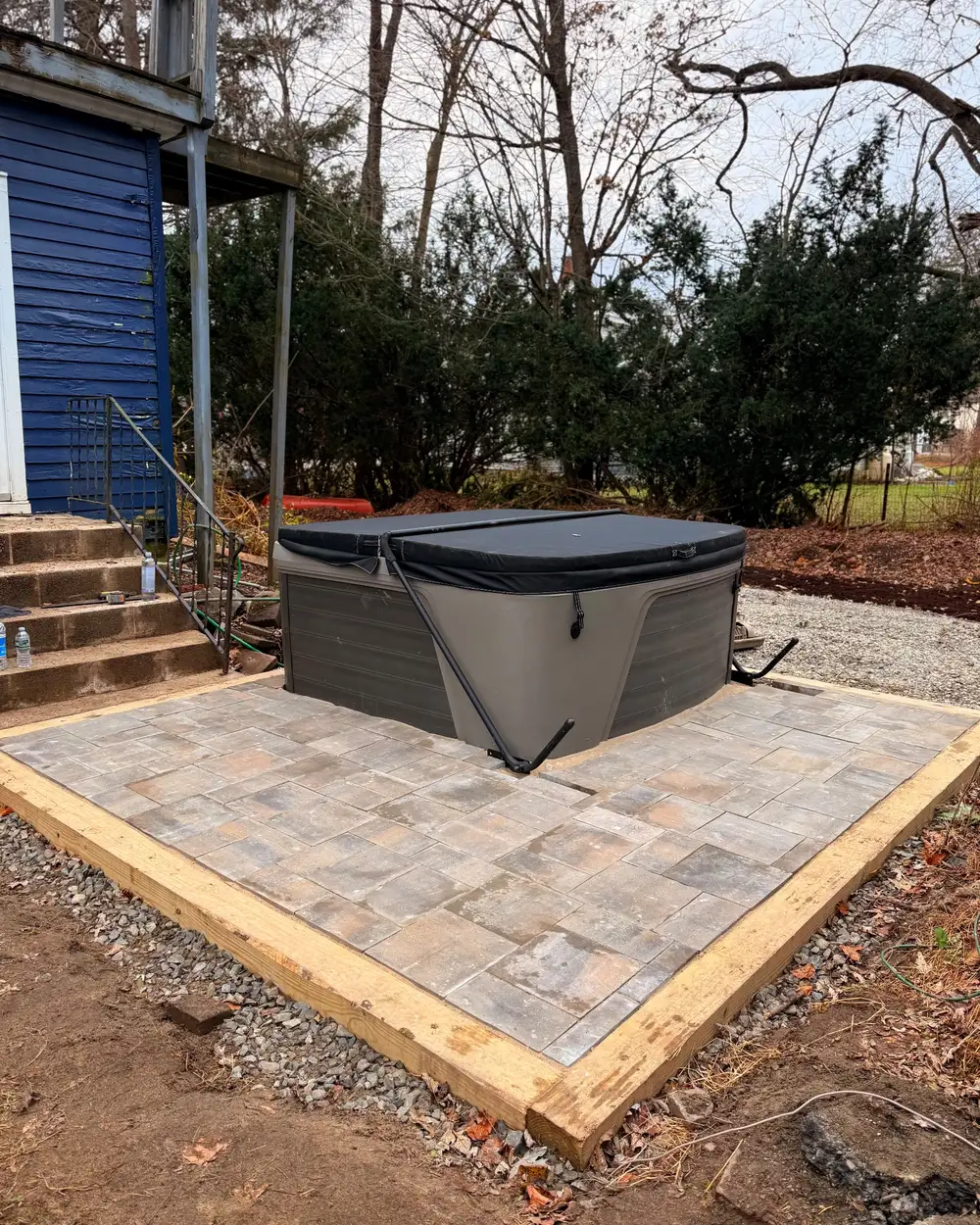 A paver pad built and squared for a hot tub beside a house