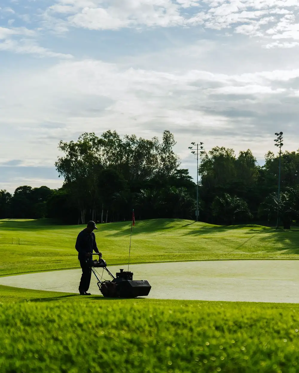 A mower crossing a wide, open stretch of kept turf